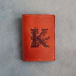 Poppy Red leather passport cover with a large floral initial K pressed into the front