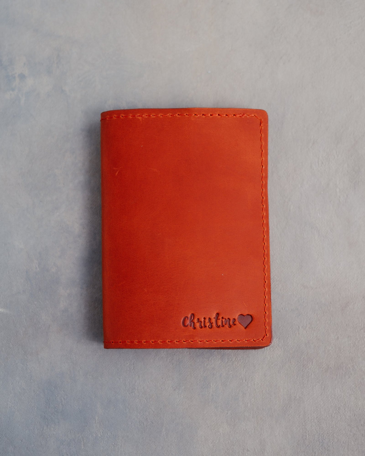 Poppy Red leather passport cover with a name in cursive with a heart pressed into the bottom corner