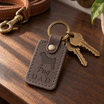 Gray Pug Dad keychain on a walnut entry table beside fanned brass keys and a coiled tan leash