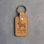 Indian Summer tan leather keychain debossed with a pug silhouette and the words Pug life CHOSE ME on gray concrete