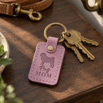 Lilac Pug Mom keychain with brass keys on a dark walnut table, a leather leash and wall hook behind