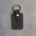 Dark espresso leather keychain debossed with a curly-tailed pug, the name Doug and THE PUG, on gray concrete