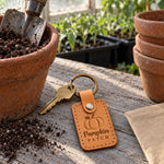 Golden tan Pumpkin Patch keychain on a hay bale beside a pile of orange pumpkins
