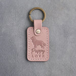 Blush pink leather keychain debossed with a golden retriever and the words Puppy LOVE, on gray concrete