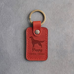 Poppy red leather keychain debossed with an Irish Setter silhouette and the words Puppy UNTIL THREE, on gray concrete