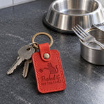 Red Pushed It Off the Table keychain on a kitchen table next to a coffee mug