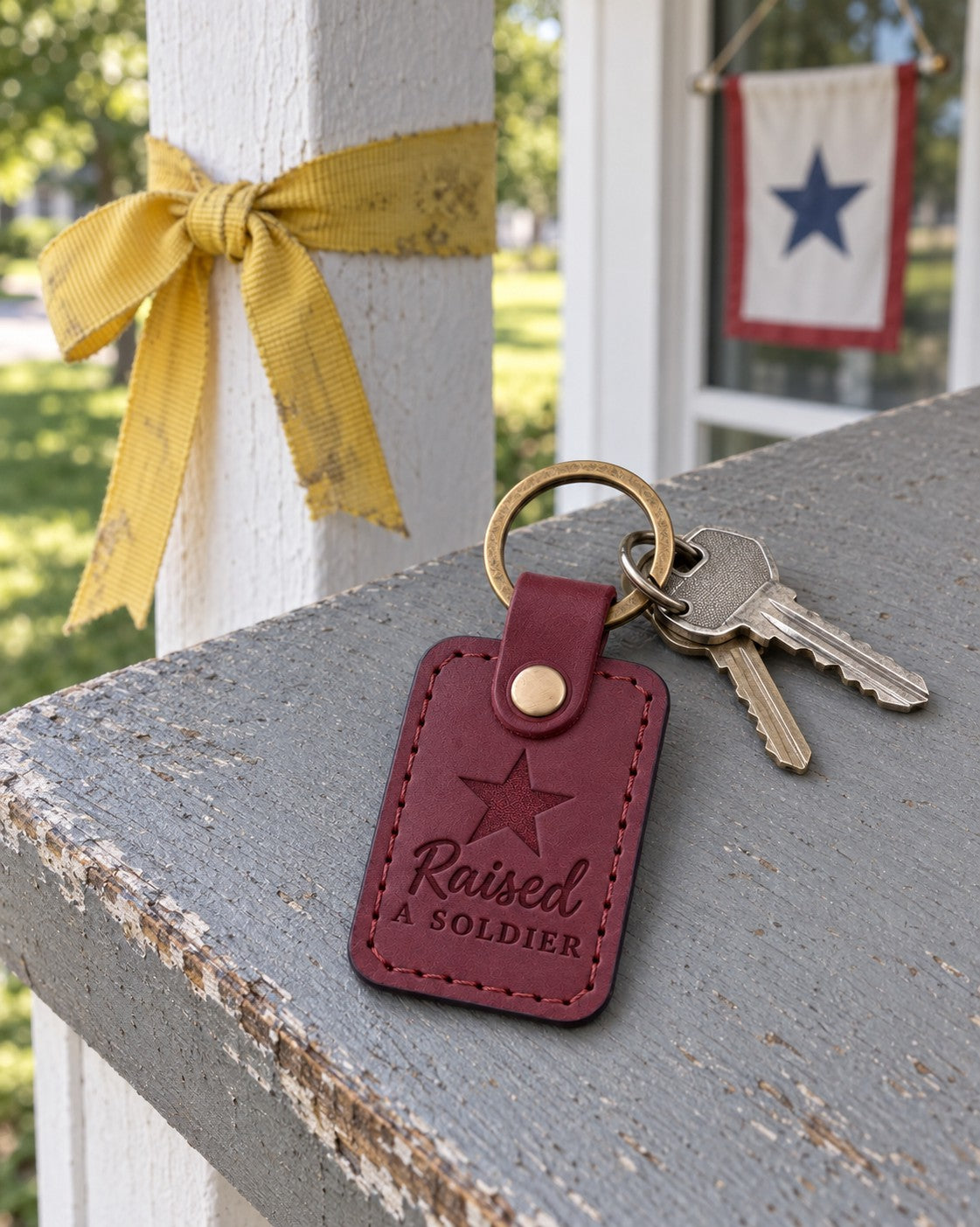 Wine red Raised a Soldier keychain on a parent's key ring resting on a folded letter from basic training