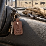 Sicilian brown Ranch DAD keychain on the ignition key of a ranch pickup, work gloves on the dash and a fence line through the windshield