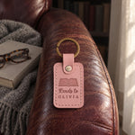 Pink Reads to OLIVIA keychain on an armchair arm beside a picture book and folded reading glasses