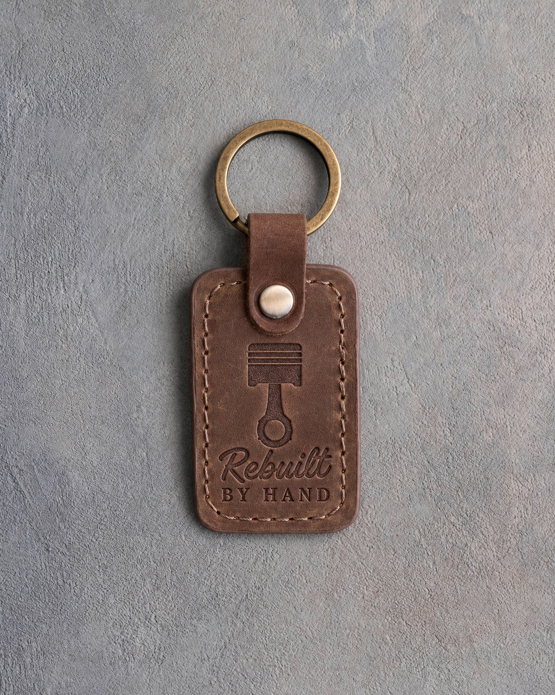 Sicilian brown leather keychain debossed with a piston and connecting rod above Rebuilt and BY HAND