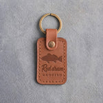 Caramel leather keychain debossed with a redfish above Red drum and REDFISH, on gray concrete