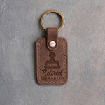 Sicilian brown leather keychain debossed with a library date stamp above Retired and LIBRARIAN, on gray concrete