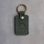 Forest green leather keychain debossed with a Rhodesian Ridgeback silhouette and the words Ridgeback DAD, on gray concrete