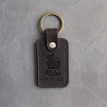 Dark espresso leather keychain debossed with a chihuahua peeking out of a handbag and the words Rides IN STYLE, on gray concrete