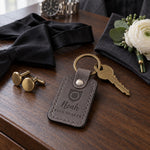 Noah RING BEARER keychain in gray leather on a walnut dresser beside a small pinned boutonniere