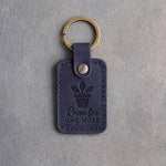 Blueberry navy leather keychain debossed with a potted plant above Room for ONE MORE, on gray concrete