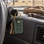 Forest green Roping PARTNER keychain on the ignition key of a ranch pickup, a stock trailer blurred in the side mirror