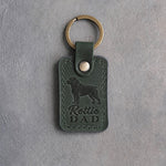 Forest green leather keychain debossed with a Rottweiler silhouette and the words Rottie DAD, on gray concrete