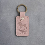 Blush pink leather keychain debossed with a Rottweiler silhouette and the words Rottie MOM, on gray concrete