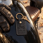 Black Rubber side DOWN motorcycle keychain hanging from the ignition of a parked bike