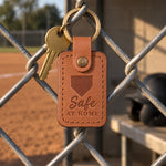 Caramel Safe at Home keychain on house keys hanging by a front door beside a baseball cap