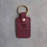 Sangria wine red leather keychain debossed with a home plate and the words Safe at home FOR CHRISTMAS, on gray plaster