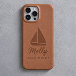 Back of a caramel leather iPhone case debossed with a sloop under full sail above Molly and FAIR WINDS below the camera, on gray plaster