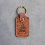 Caramel leather keychain debossed with a sloop under full sail above Molly and FAIR WINDS, on gray plaster