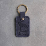 Blueberry navy leather keychain debossed with a Saint Bernard silhouette and Saint DAD on gray concrete