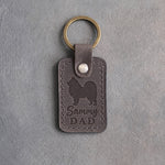Country gray leather keychain debossed with a Samoyed silhouette and Sammy DAD, on gray concrete