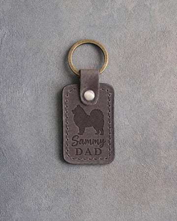 Country gray leather keychain debossed with a Samoyed silhouette and Sammy DAD, on gray concrete