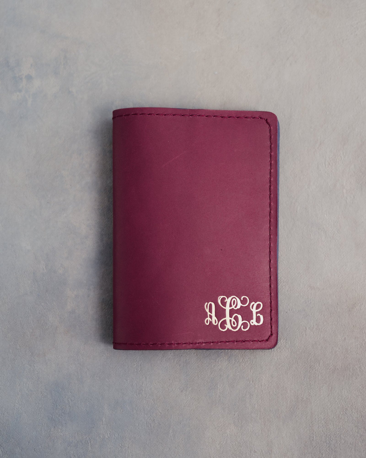 Sangria leather passport cover with a vine monogram pressed into the bottom corner