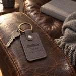 Gray Sat on the Keyboard keychain lying beside a laptop keyboard on a home office desk