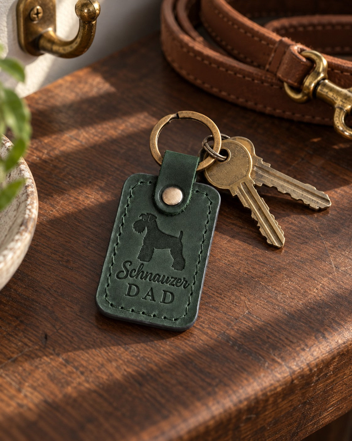 Forest green Schnauzer Dad leather keychain held in a warm everyday setting