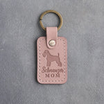 Blush pink leather keychain debossed with a Miniature Schnauzer silhouette and the words Schnauzer MOM, on gray concrete
