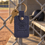 Navy Senior Night keychain held in a player's hand on a field under stadium lights