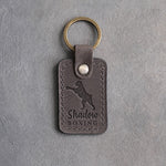 Country gray leather keychain debossed with a boxer on its hind legs throwing a jab and the words Shadow BOXING, on gray concrete