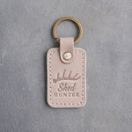 Gray sand leather keychain debossed with a single shed antler above the words Shed HUNTER, on gray plaster