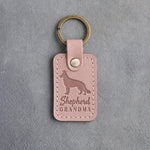 Blush pink leather keychain debossed with a German shepherd silhouette and the words Shepherd GRANDMA, on gray concrete