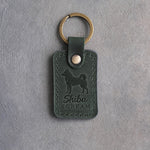 Forest green leather keychain debossed with a Shiba Inu silhouette and the words Shiba SCREAM, on gray concrete
