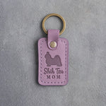Lilac leather keychain debossed with a Shih Tzu silhouette and the words Shih Tzu MOM, on gray concrete