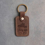 Sicilian brown leather keychain debossed with a semi truck above the words Shiny side and UP, on gray plaster