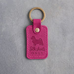 Fuchsia pink leather keychain debossed with a Maltese silhouette and the words Silk sheets ONLY, on gray concrete