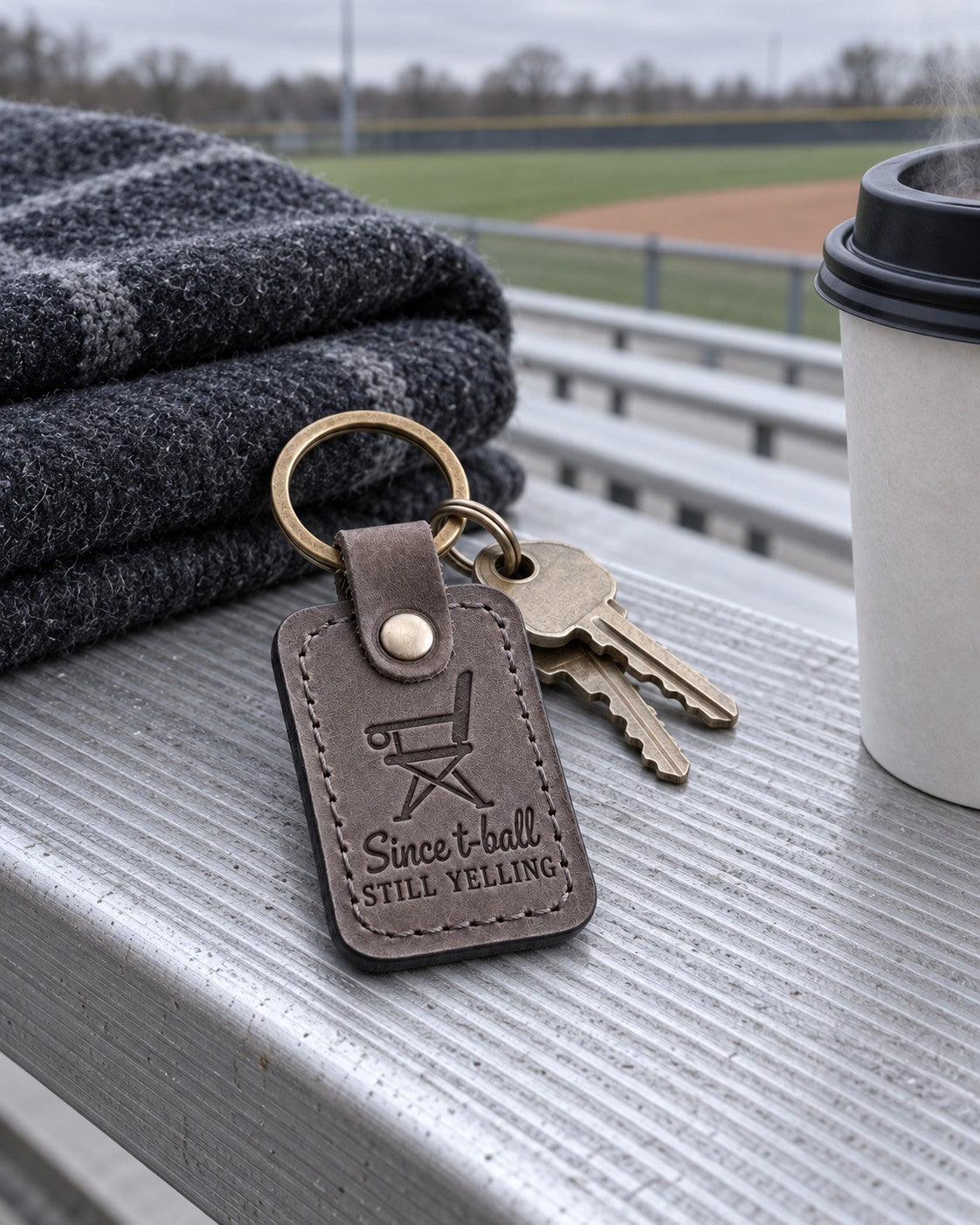 Gray Still Yelling keychain on car keys tucked into the cup holder of a folding sports chair