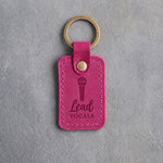 Fuchsia pink leather keychain debossed with a handheld microphone above the words Lead and VOCALS, on gray concrete