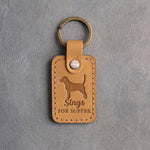 Indian Summer tan leather keychain debossed with a beagle silhouette and the words Sings FOR SUPPER, on gray concrete