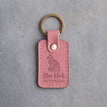 Parisian blossom pink leather keychain debossed with a sitting cat above the words Slow blink RETURNED