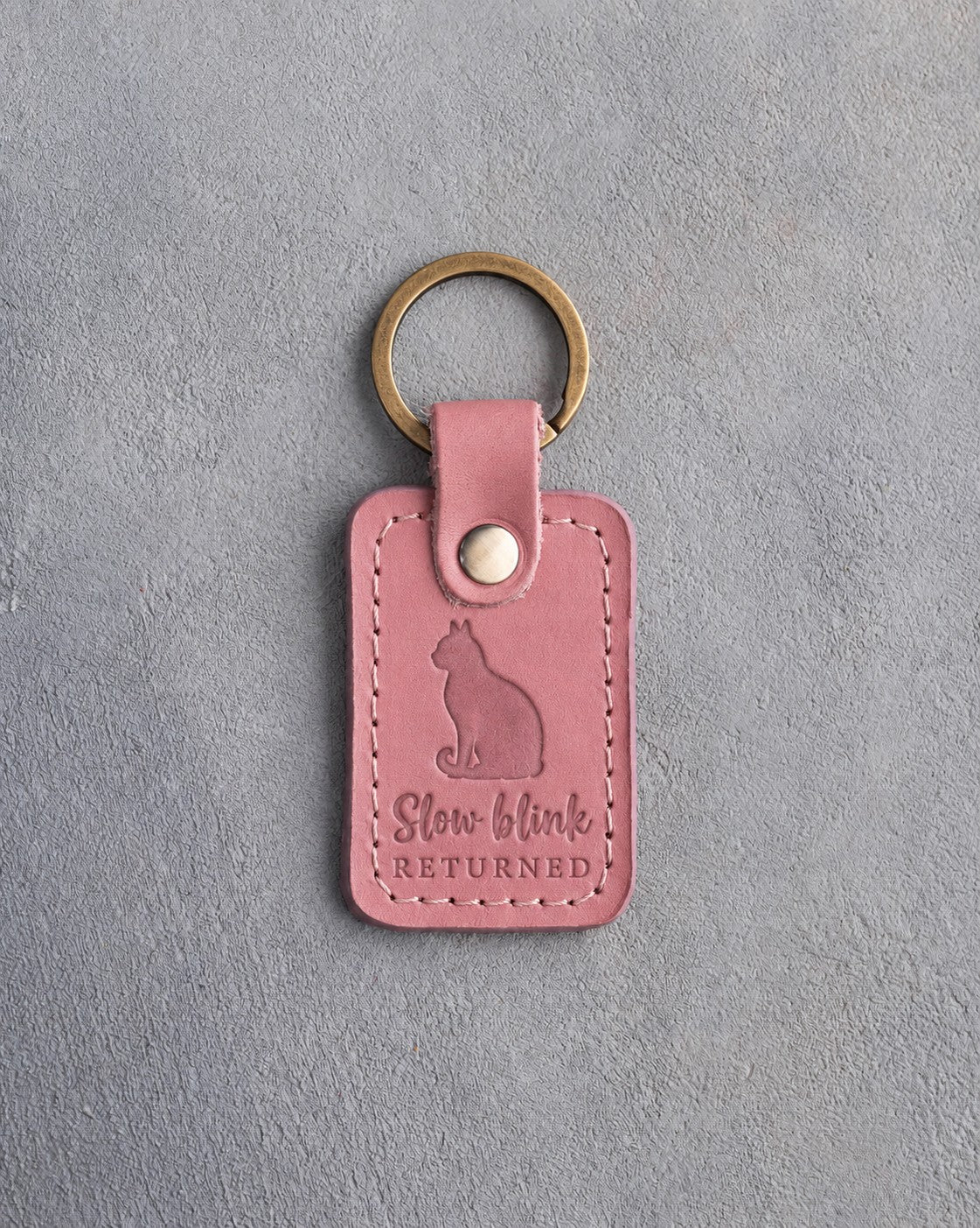 Parisian blossom pink leather keychain debossed with a sitting cat above the words Slow blink RETURNED