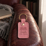 Pink Smells THE PAGES keychain resting on a fanned-open secondhand book in a sunny bookshop window