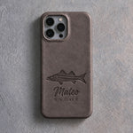 Back of a country gray leather iPhone case debossed with a snook above Mateo and SNOOK below the camera, on gray plaster